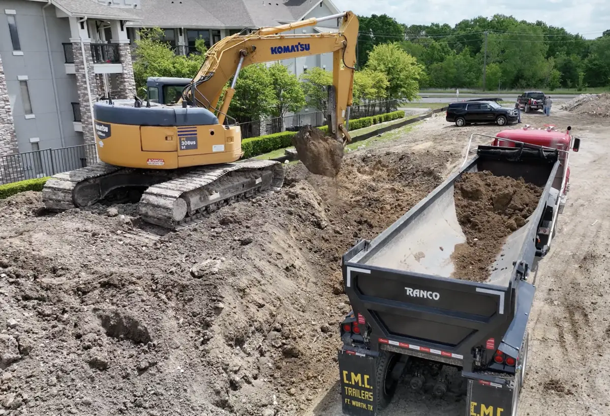 Excavator loading surplus soil into a haul truck for export from a Texas job site